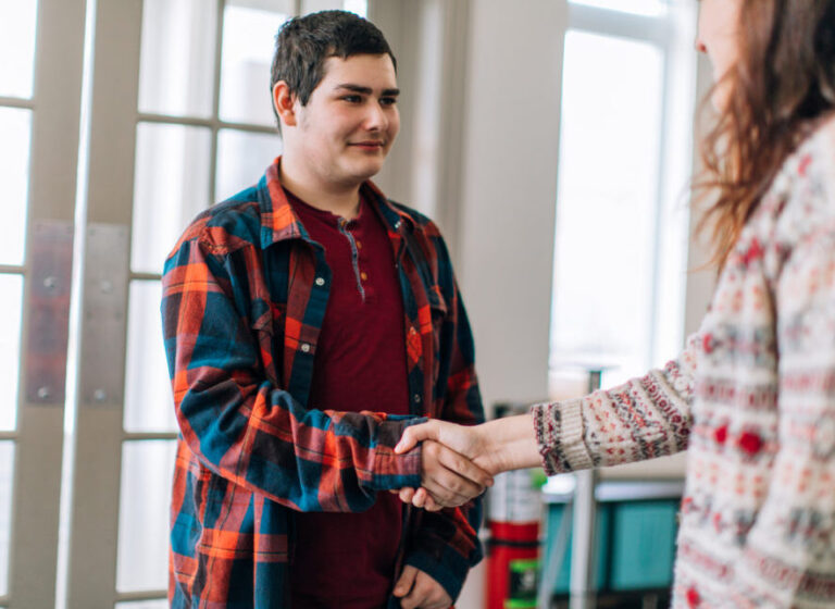 A young woman and a teenage boy shaking hands. Social services, social worker, psychologist, psychiatrist, foster home, student and teacher